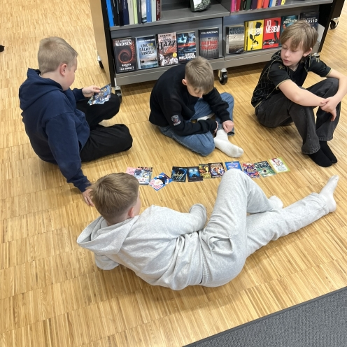 Fire drenge, der sidder på gulvet og kigger på bogforsider