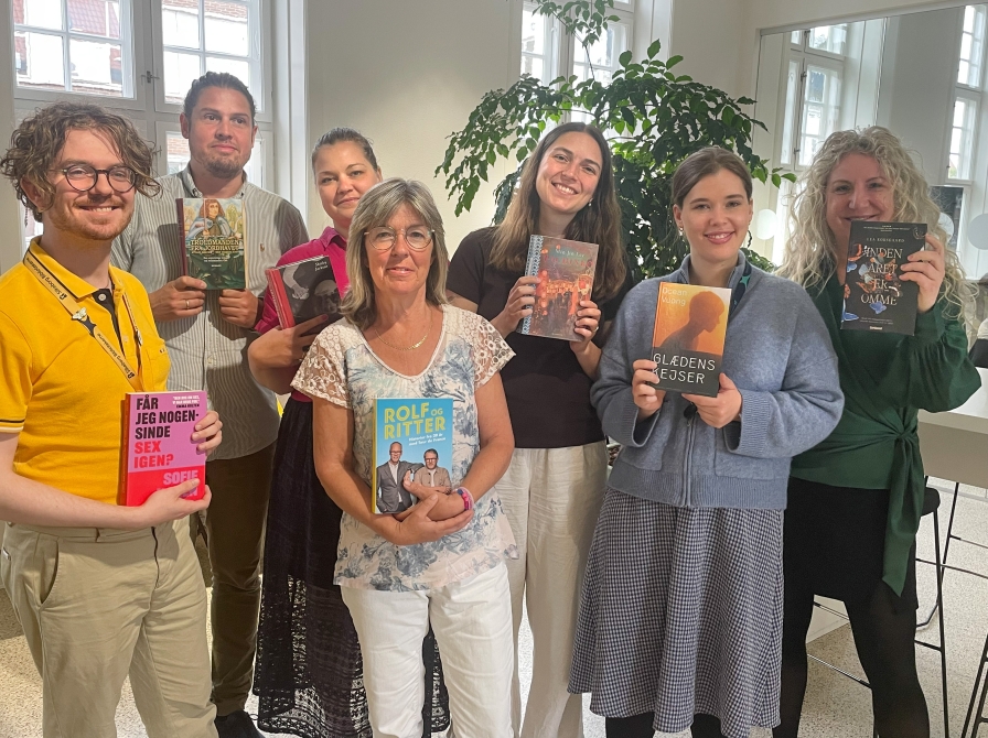 Foto af 7 mennesker med en bog i hånden