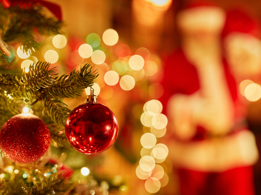 Julekugler på en juletræsgren og en sløret julemand i baggrunden