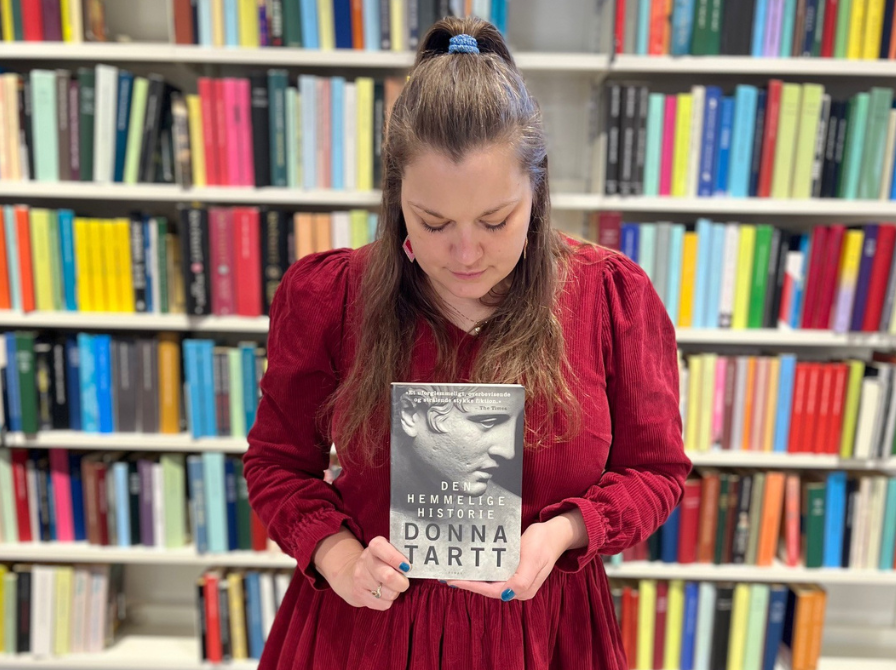 Formidler Josefine i biblioteksrummet med romanen "Den hemmelige historie" i hænderne